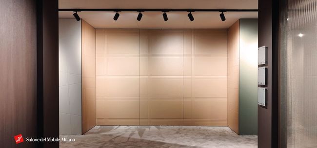 Stanza moderna vuota con pareti beige rivestite a pannelli, pavimento in marmo grigio e faretti su binario neri sul soffitto