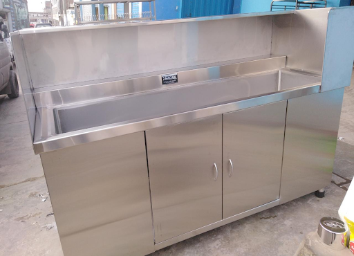 Armario fregadero comercial de acero inoxidable con salpicadero y módulo de almacenamiento de dos puertas en un taller