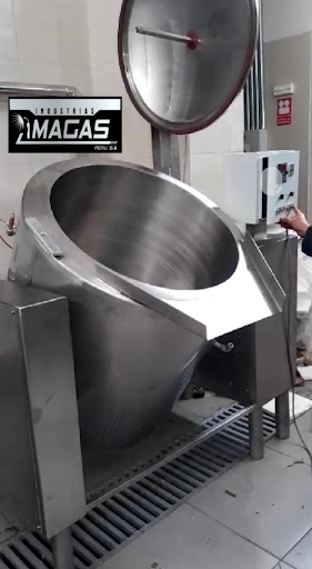 Gran mezcladora industrial de acero inoxidable con tambor abierto e inclinado, en una fábrica