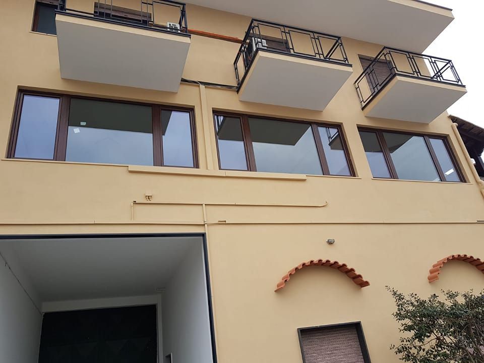 Edificio beige con finestre con cornici marroni, balconi e ingresso ad arco.