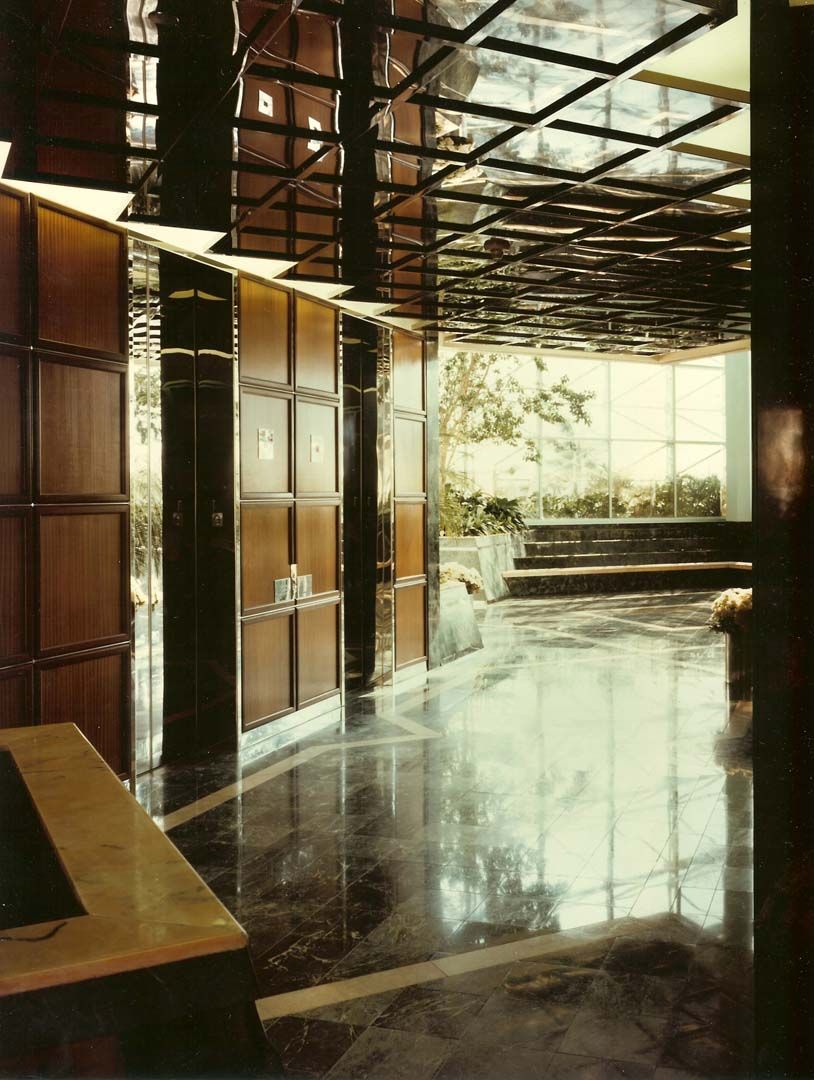 Elegant interior with glossy black floors, wood paneling, mirrored ceiling, and large windows leading to a patio.