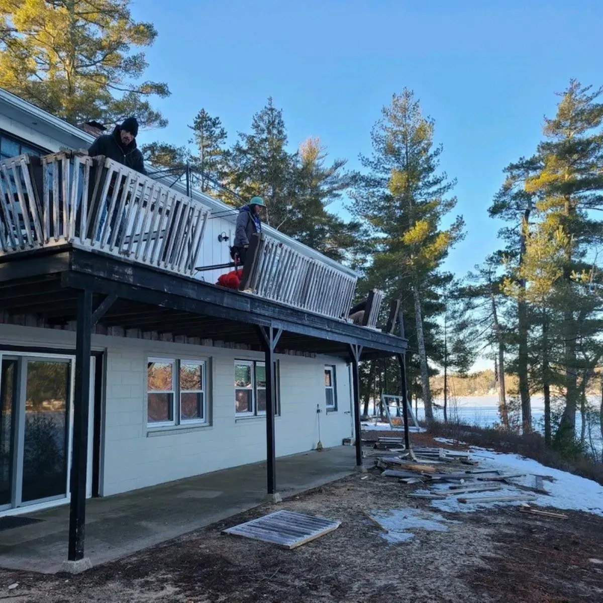 A man is standing on a balcony overlooking a lake.