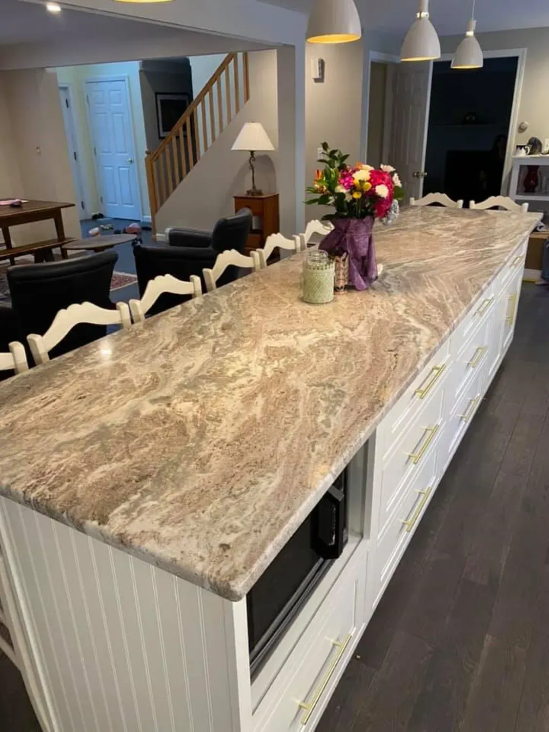 A kitchen with a large granite counter top and white cabinets.