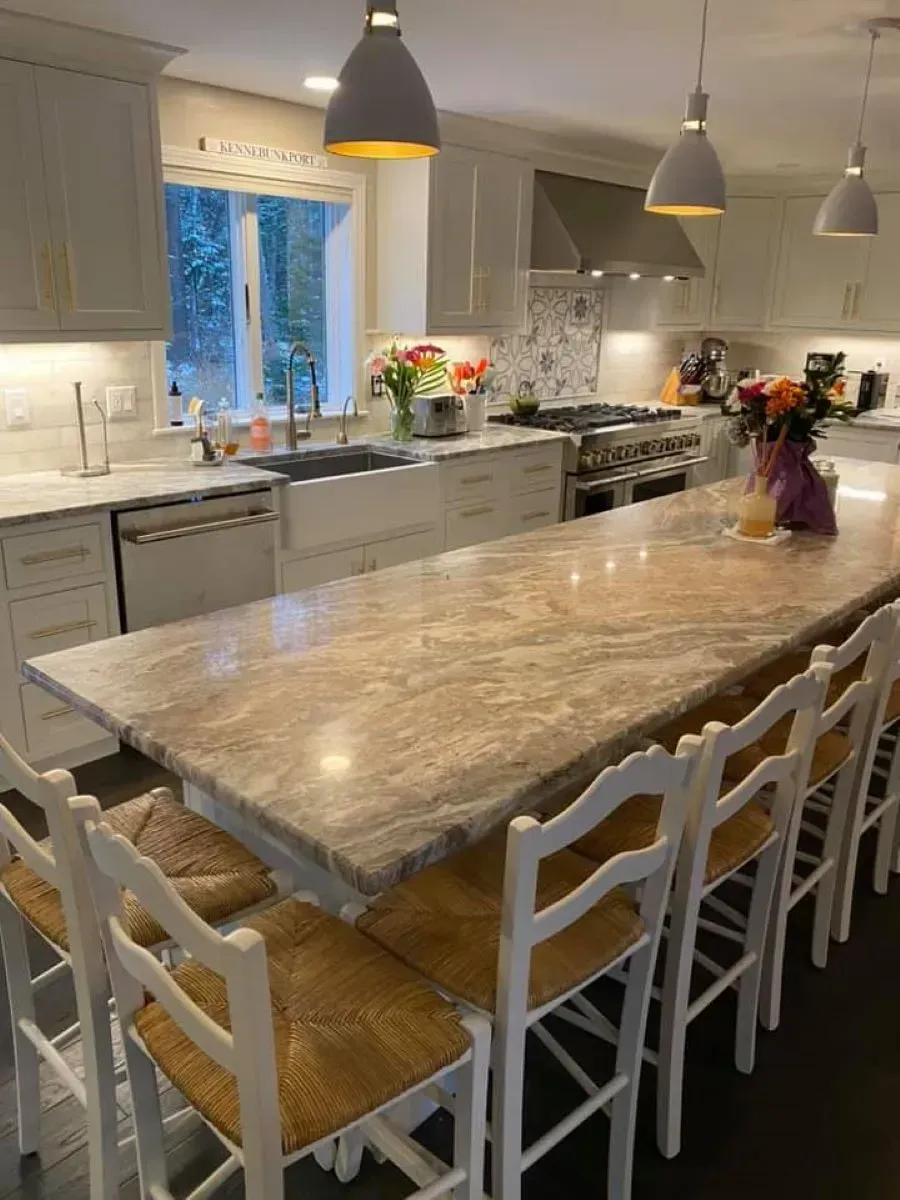 A kitchen with a long table and chairs and a large island.