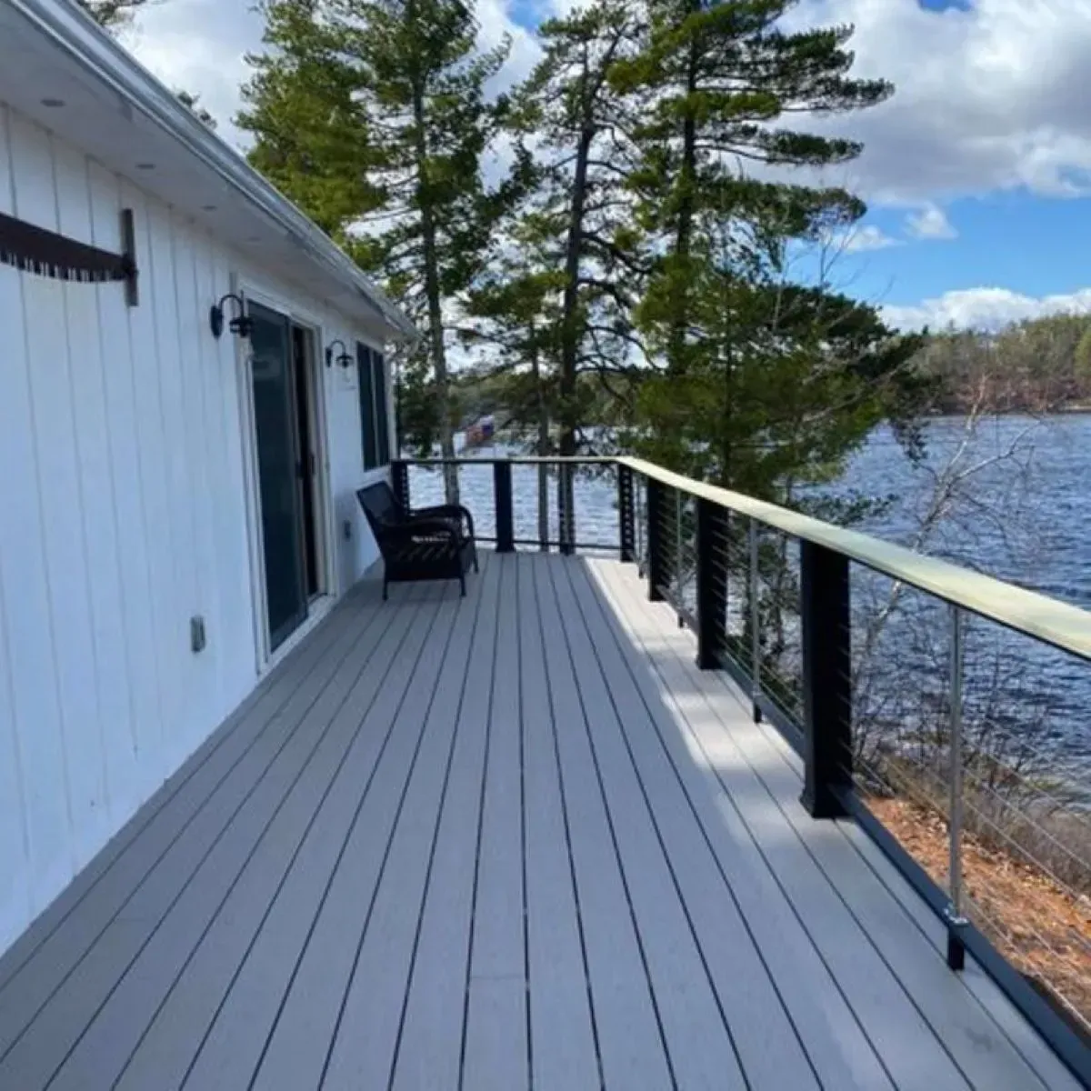 A white house with a large deck overlooking a lake