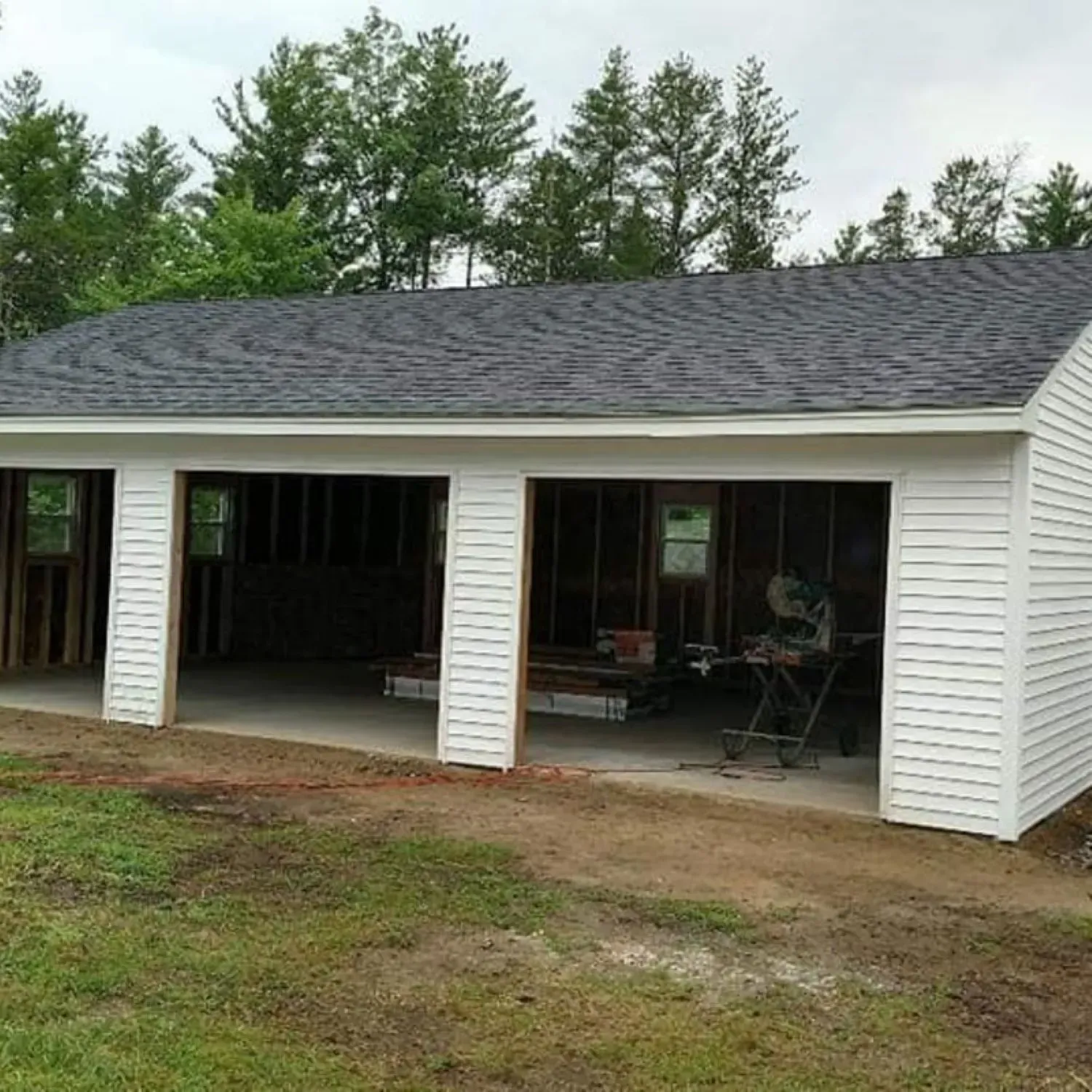 A white garage with a black roof is being built.