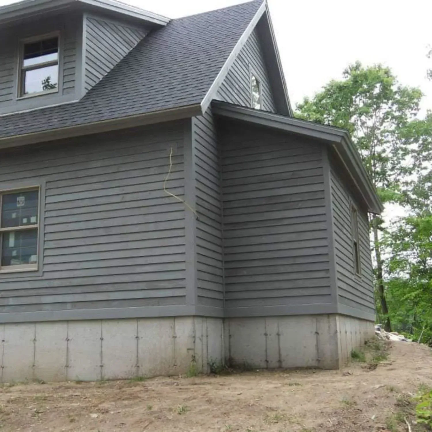 A gray house with a black roof and a lot of windows