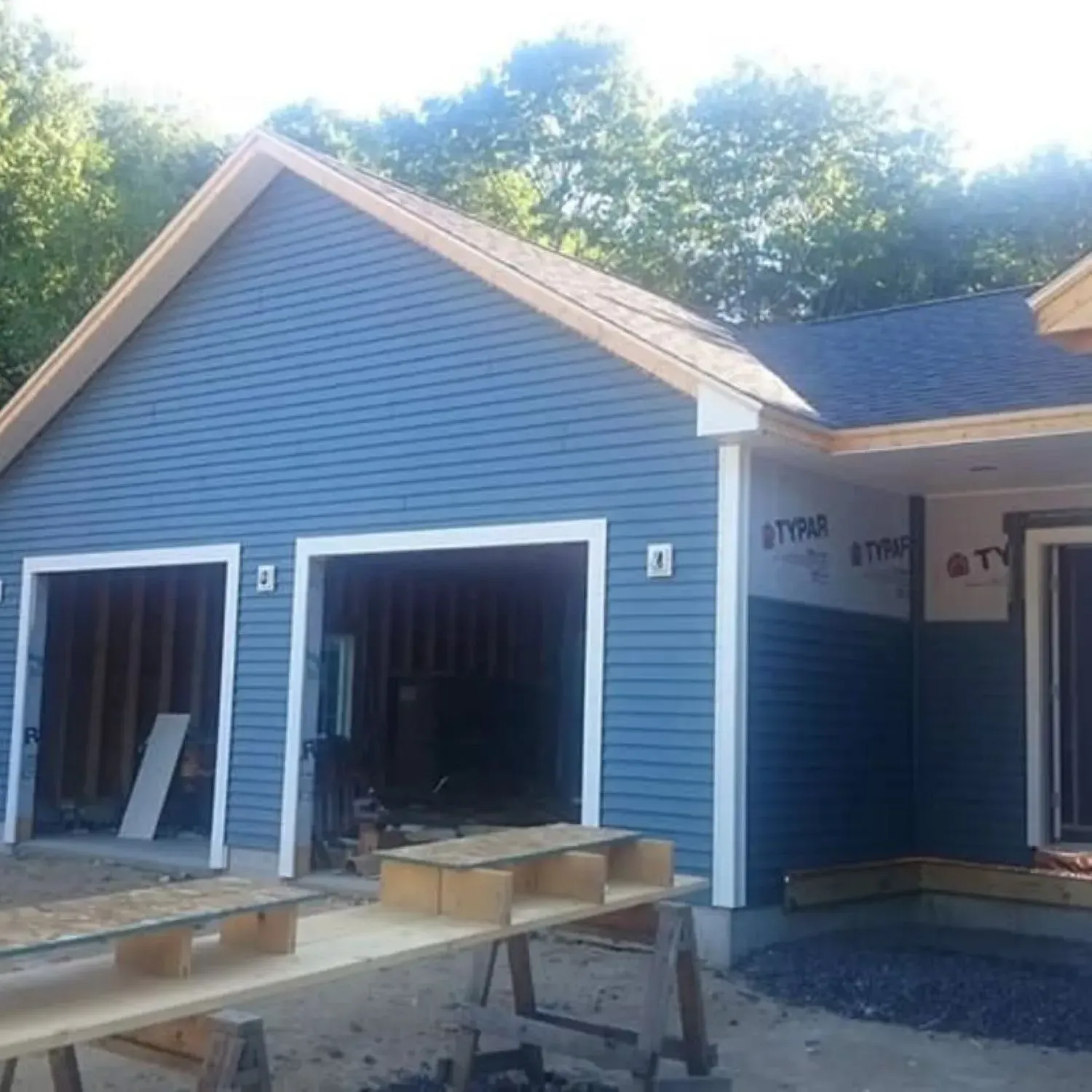 A blue house is being built with two garage doors