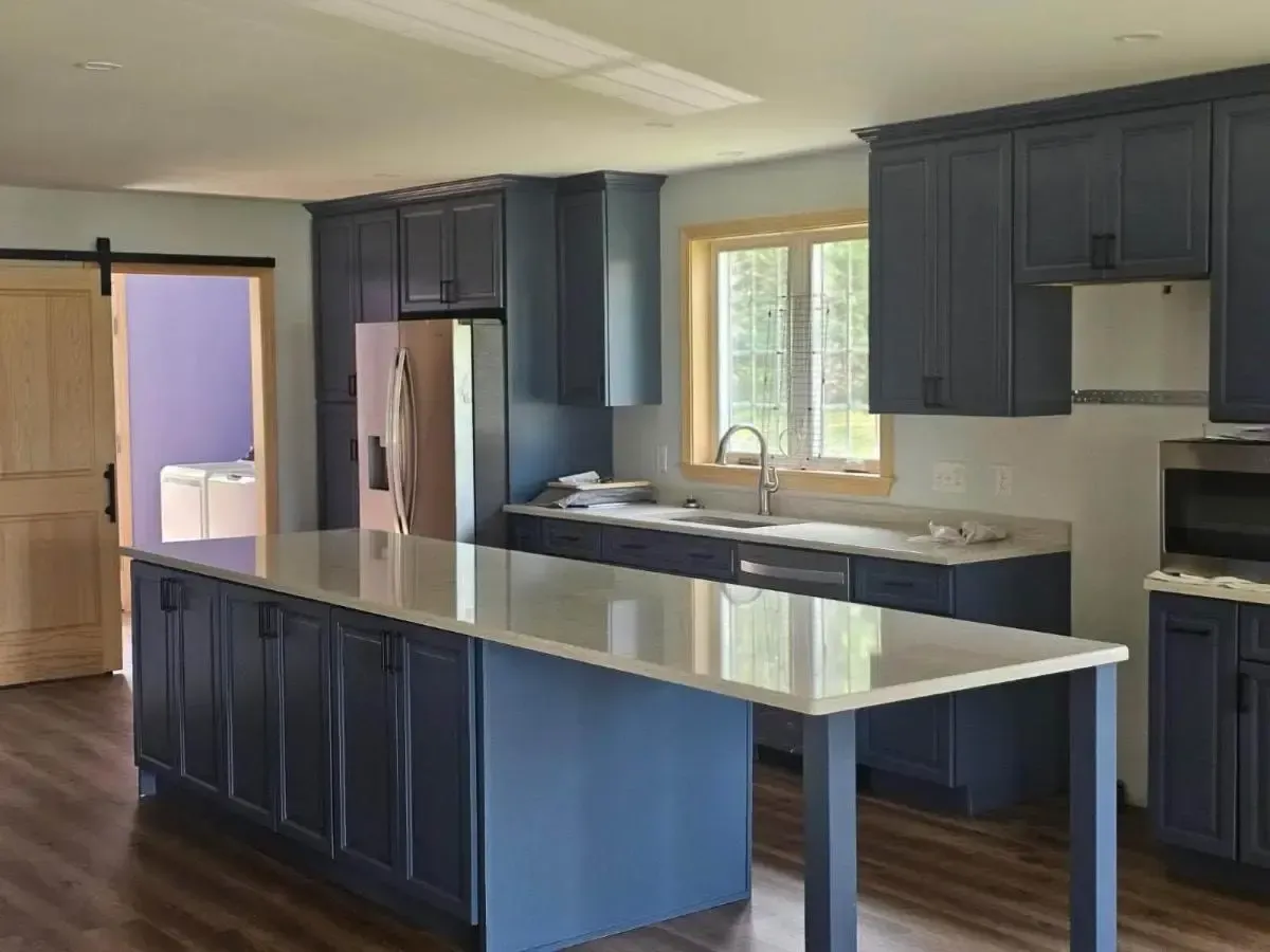 Modern kitchen with dark blue cabinets, granite island, and a window over the sink