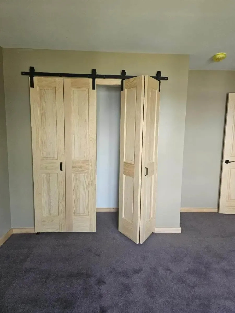 Sliding barn doors on a beige wall in a carpeted room, one door partly open.