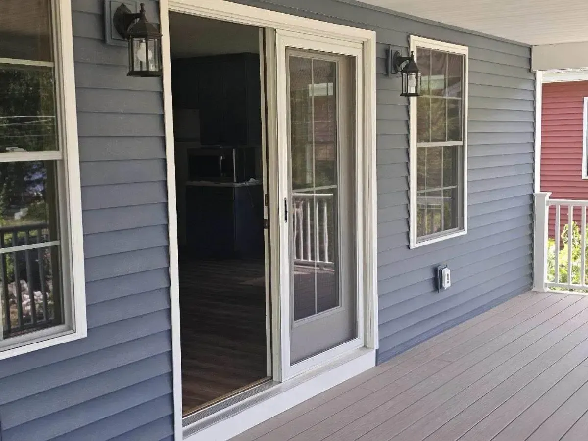 Blue house porch with gray siding, white-framed windows, and a sliding glass door