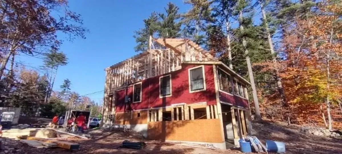 A large red house is being built in the middle of a forest.