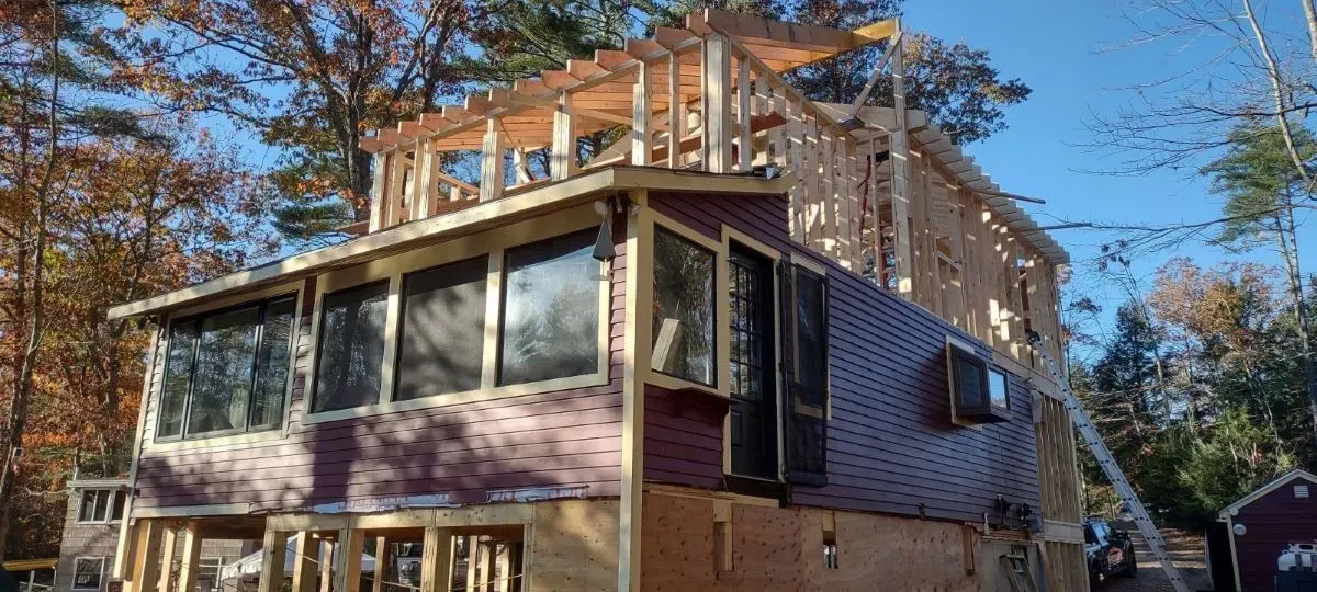 A house is being built in the woods with a lot of windows.