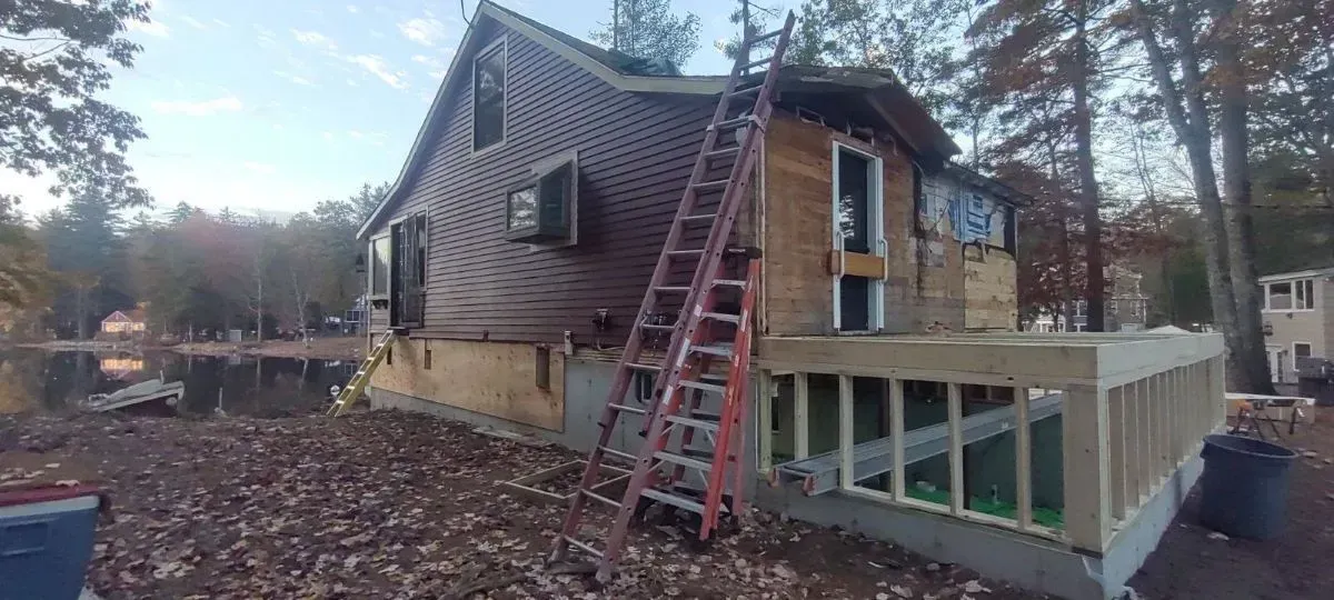A house is being remodeled with a ladder on the side of it.