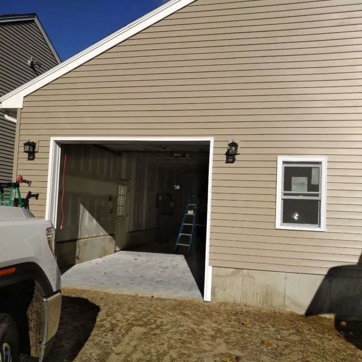 A truck is parked in front of a house with a garage door open.