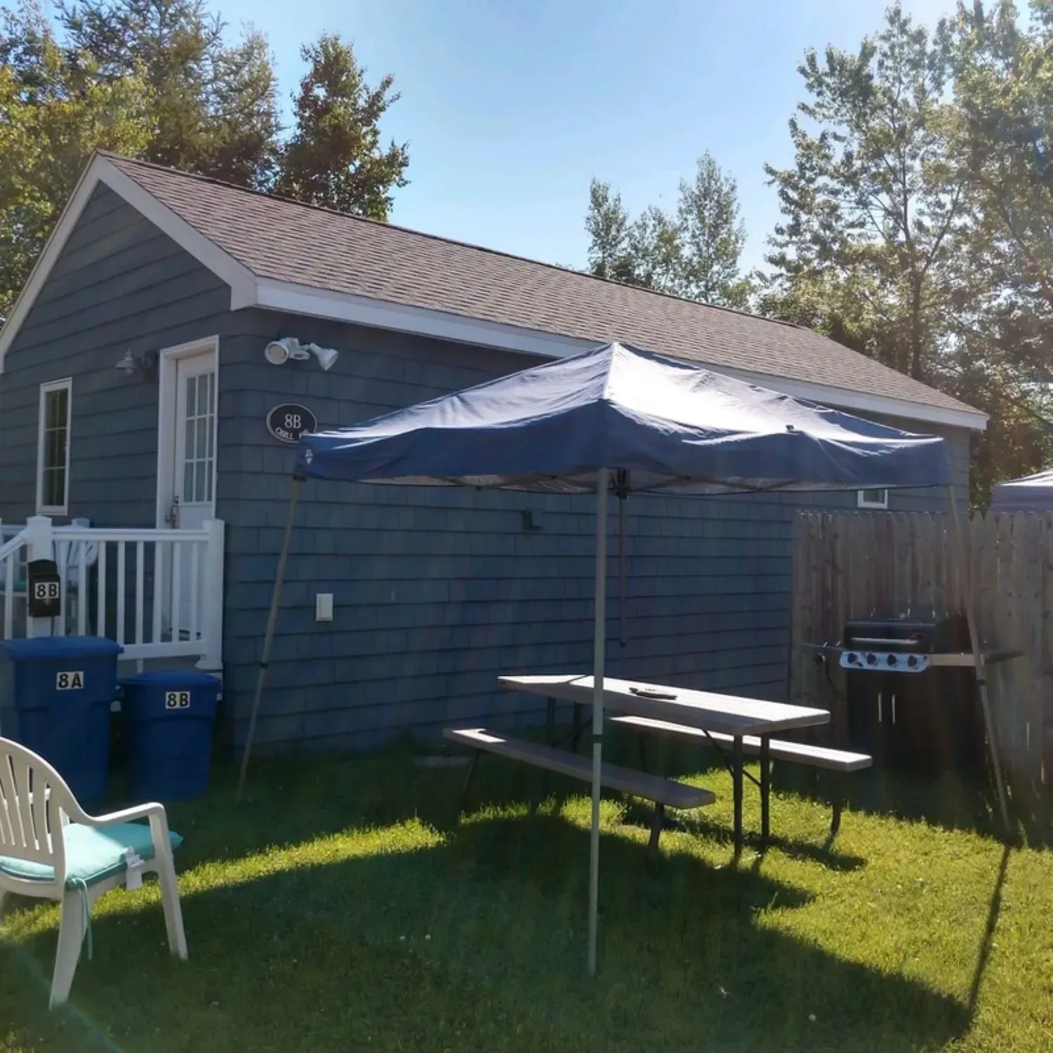 A small house with a blue umbrella in front of it