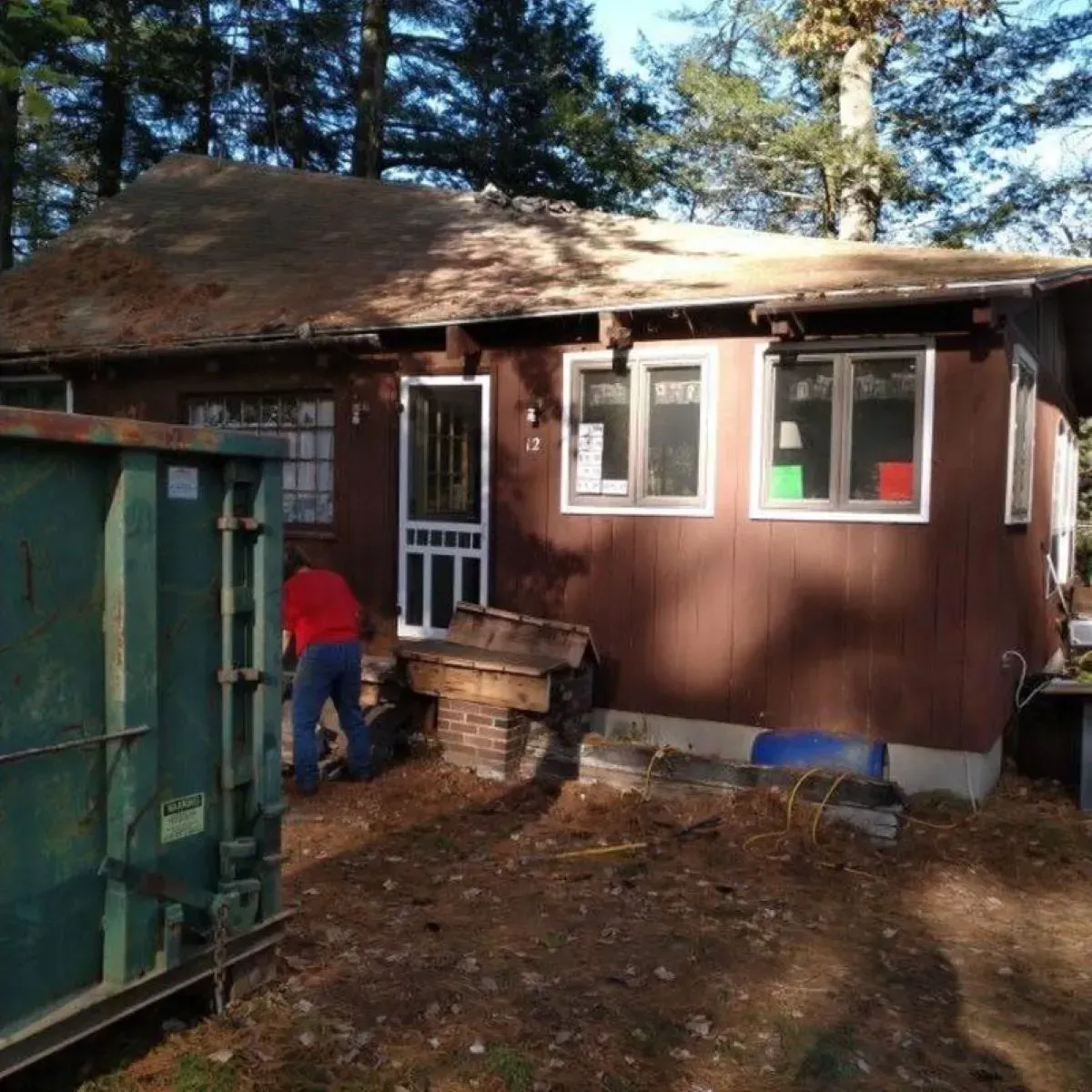 A brown house with a green dumpster in front of it