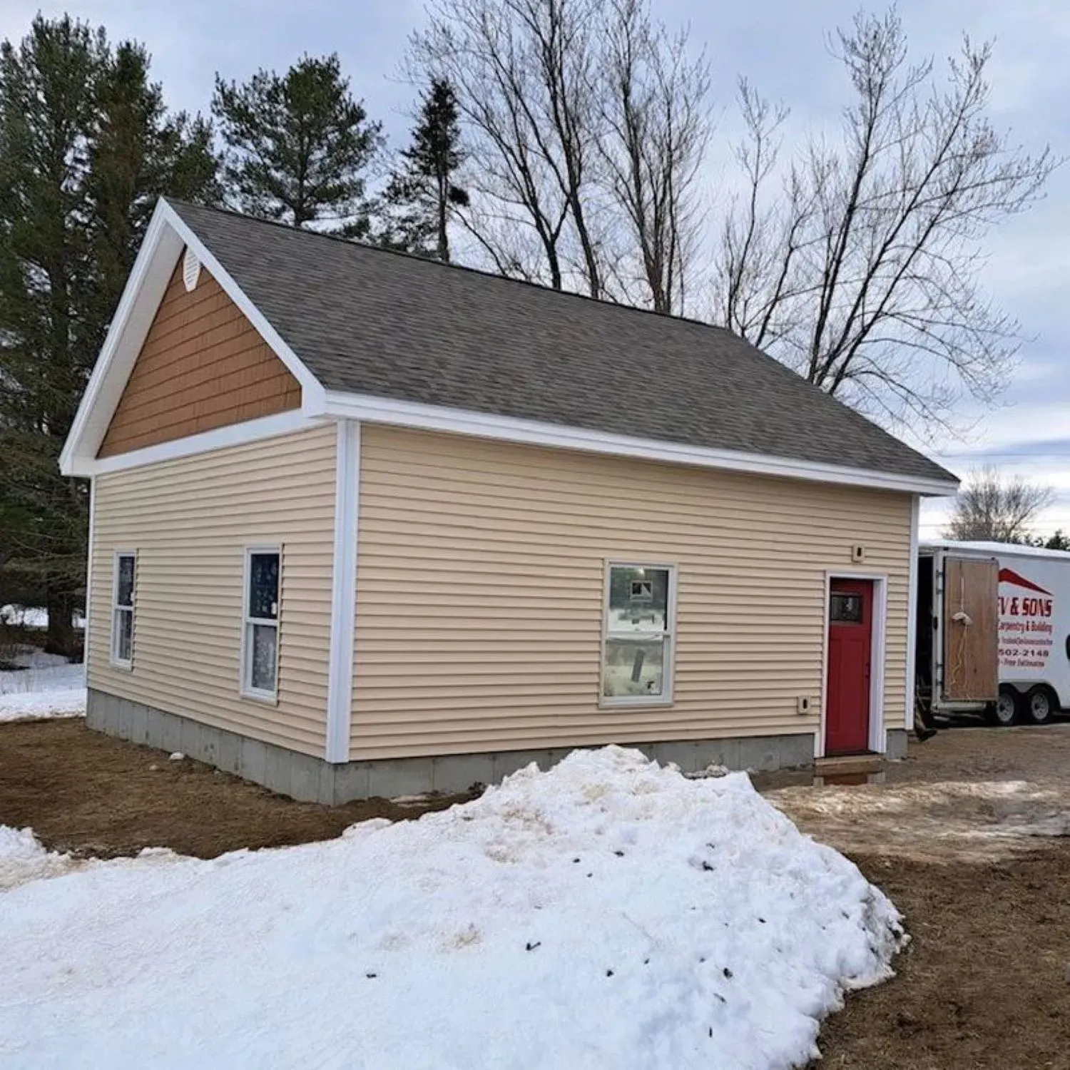 A small house with a red door and a moving truck parked in front of it