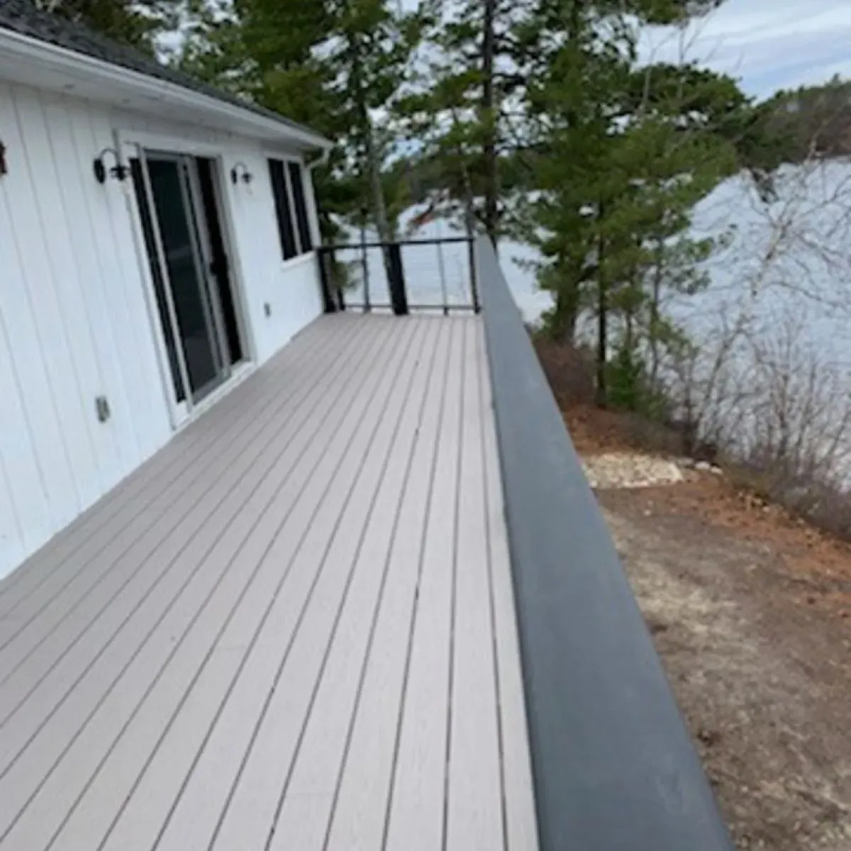 A white house with a large deck overlooking a lake