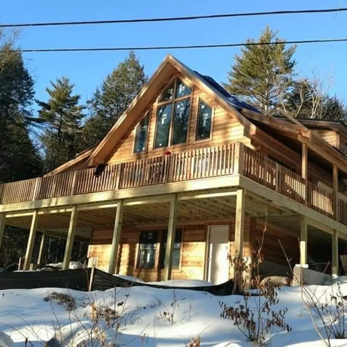 A large wooden house with a large deck in the snow