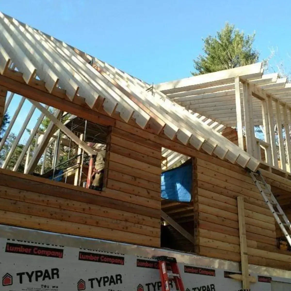 A ladder is on the side of a log cabin under construction