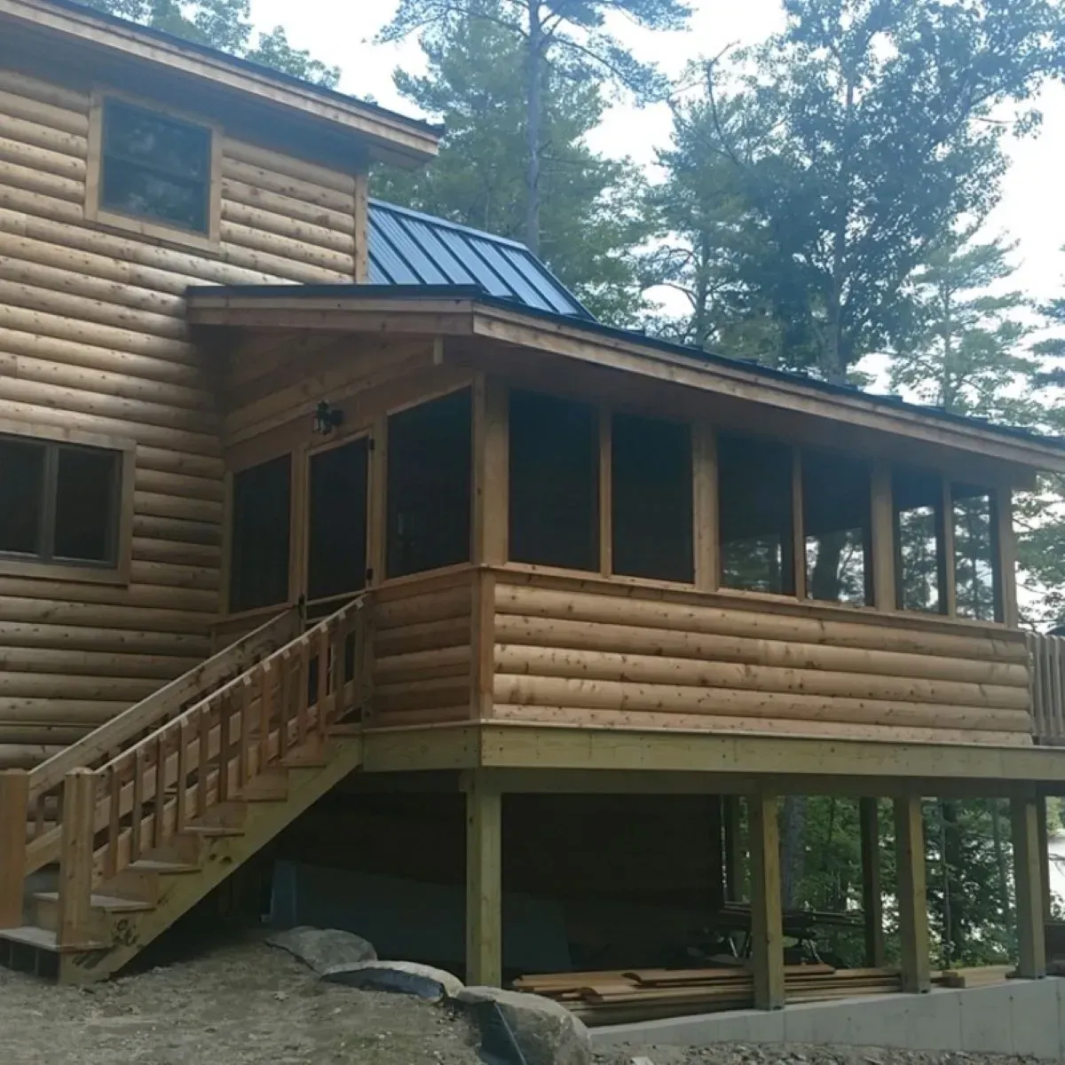 A log cabin with a screened in porch and stairs