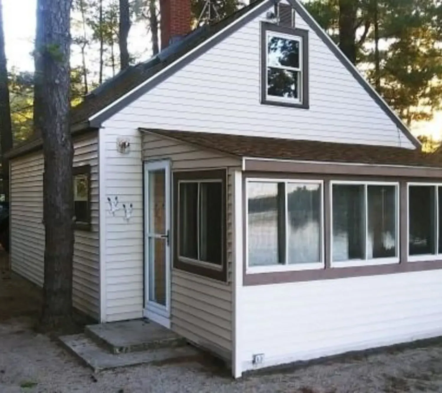 A small white house with a porch and a lot of windows