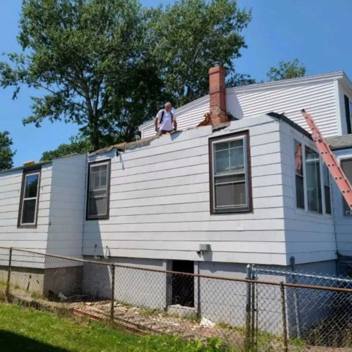 A man is standing on the roof of a white house