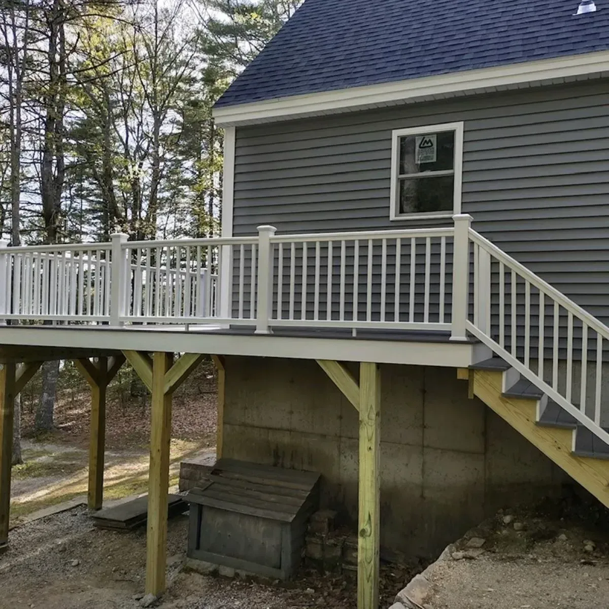 A gray house with a white deck and stairs