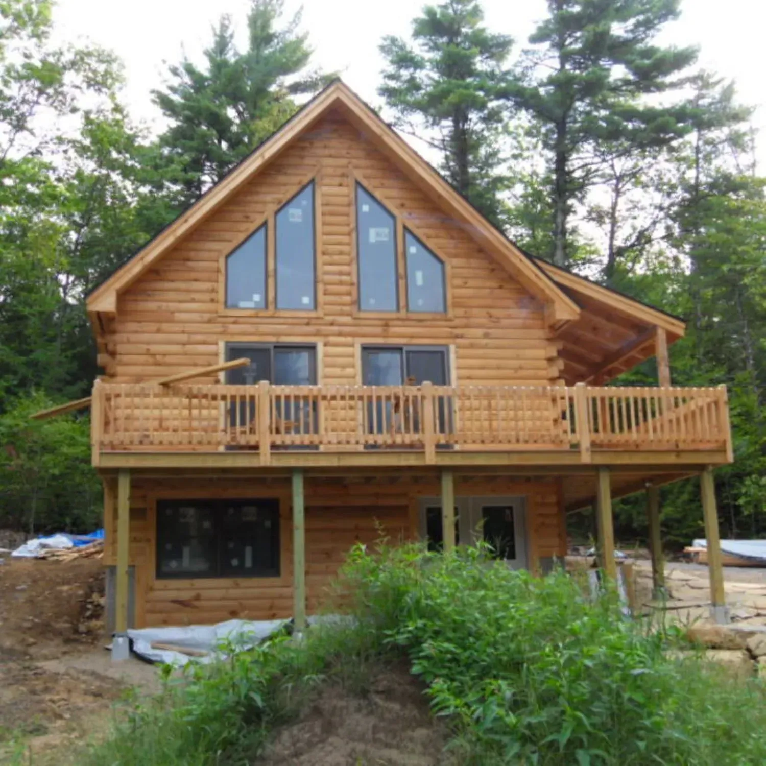 A log cabin with a large deck in the middle of the woods