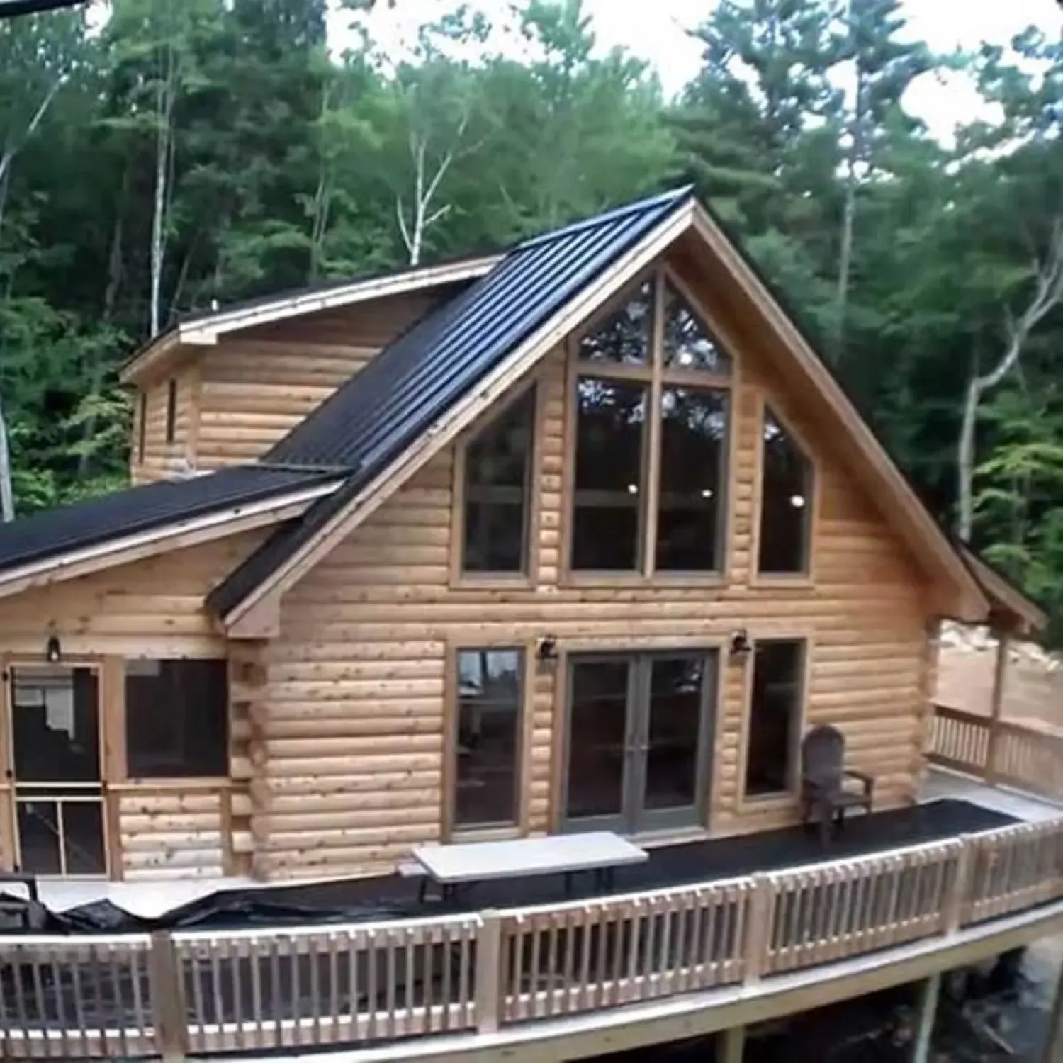 A large log cabin with a black roof and lots of windows