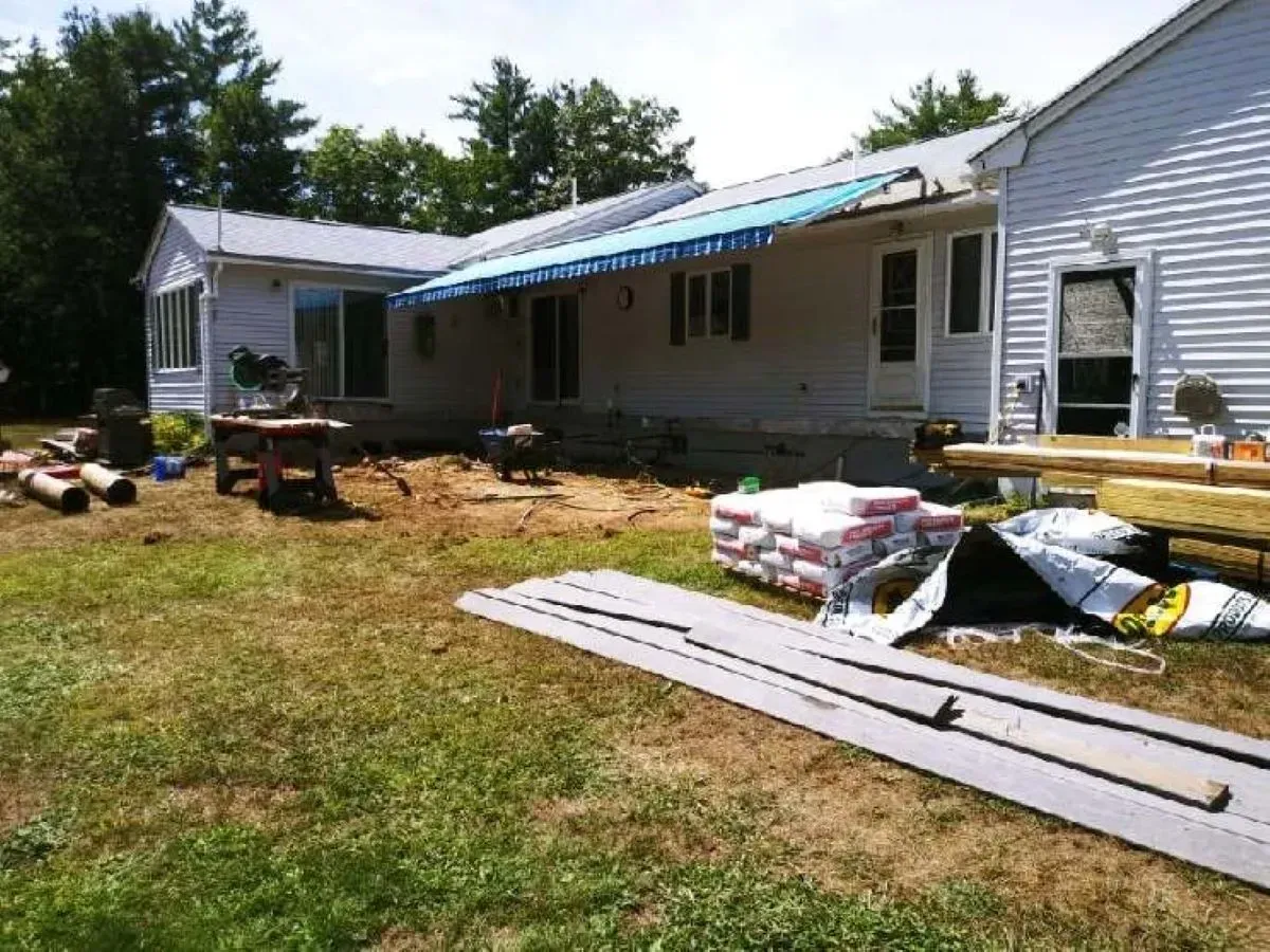 A white house with a blue awning is being remodeled