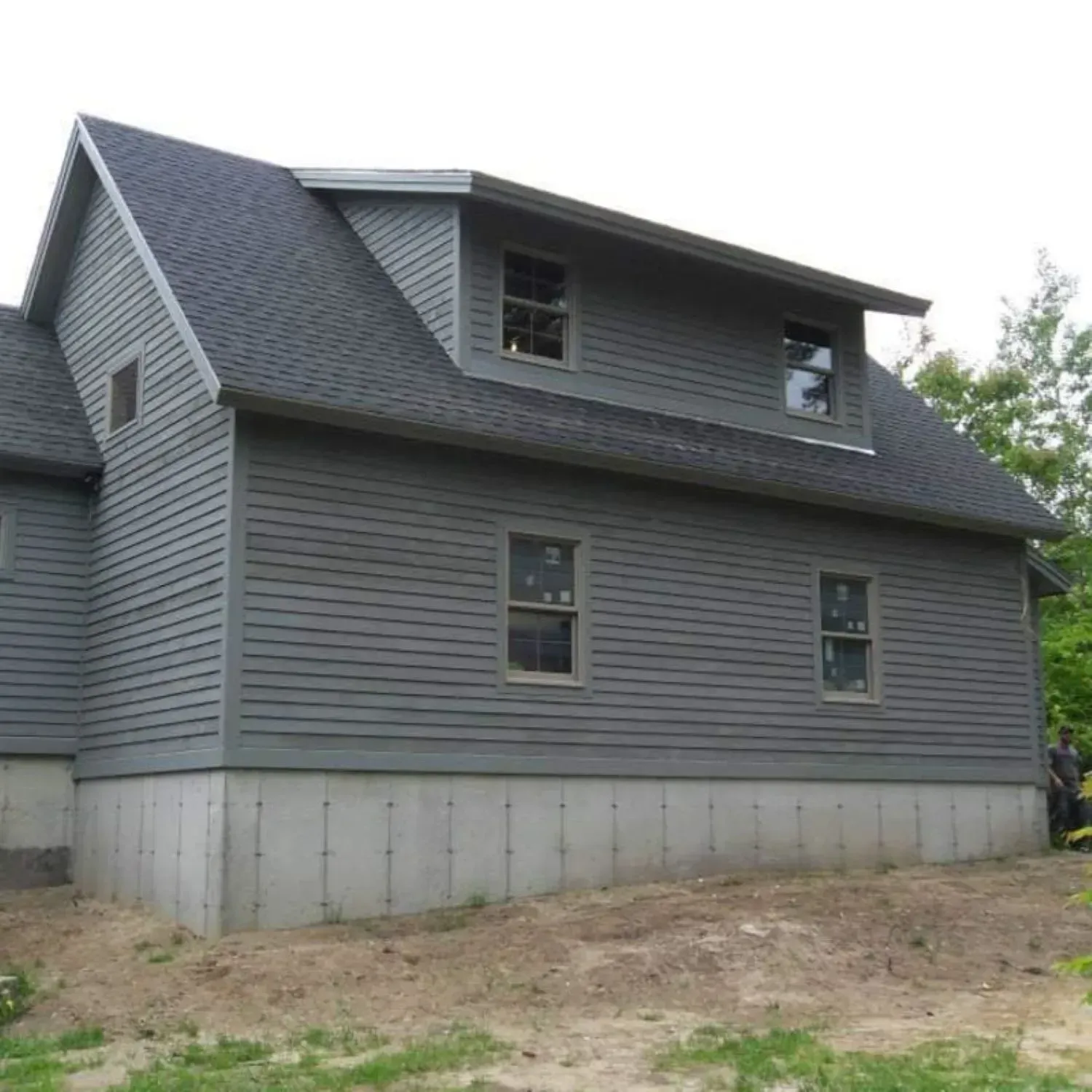A gray house with a black roof and a lot of windows