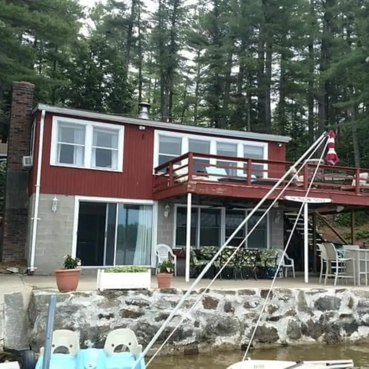 A boat is docked in front of a house with a large deck