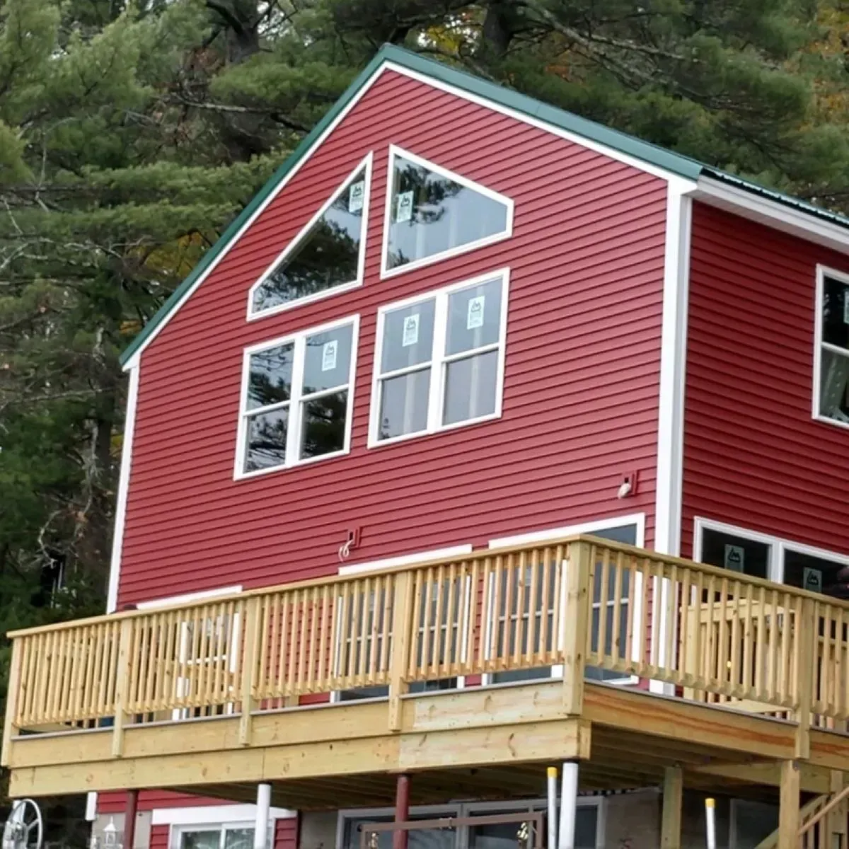 A red house with a wooden deck and a green roof