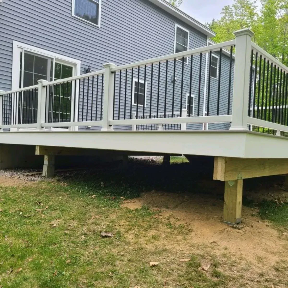 A white deck with a black railing is in front of a house.