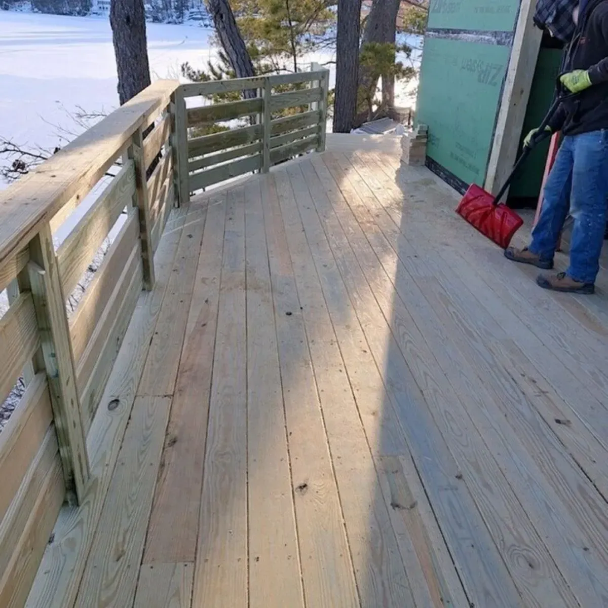A man standing on a wooden deck with a red bag