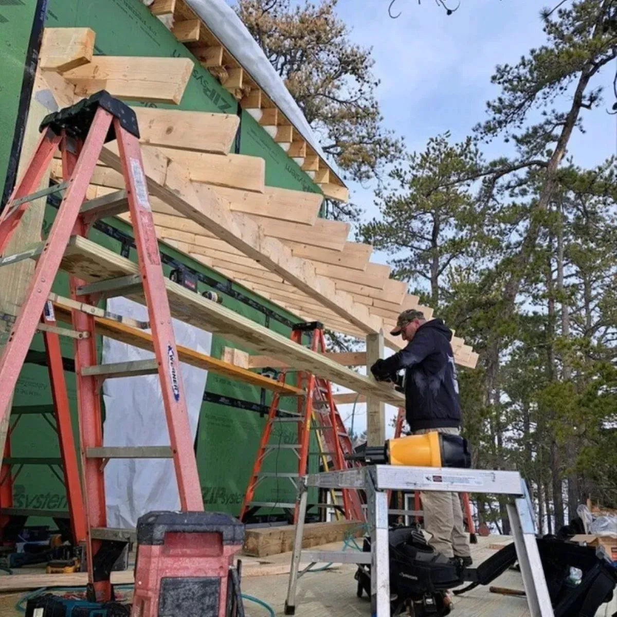 A man on a ladder is working on a wooden structure