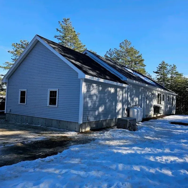A house with snow on the ground in front of it