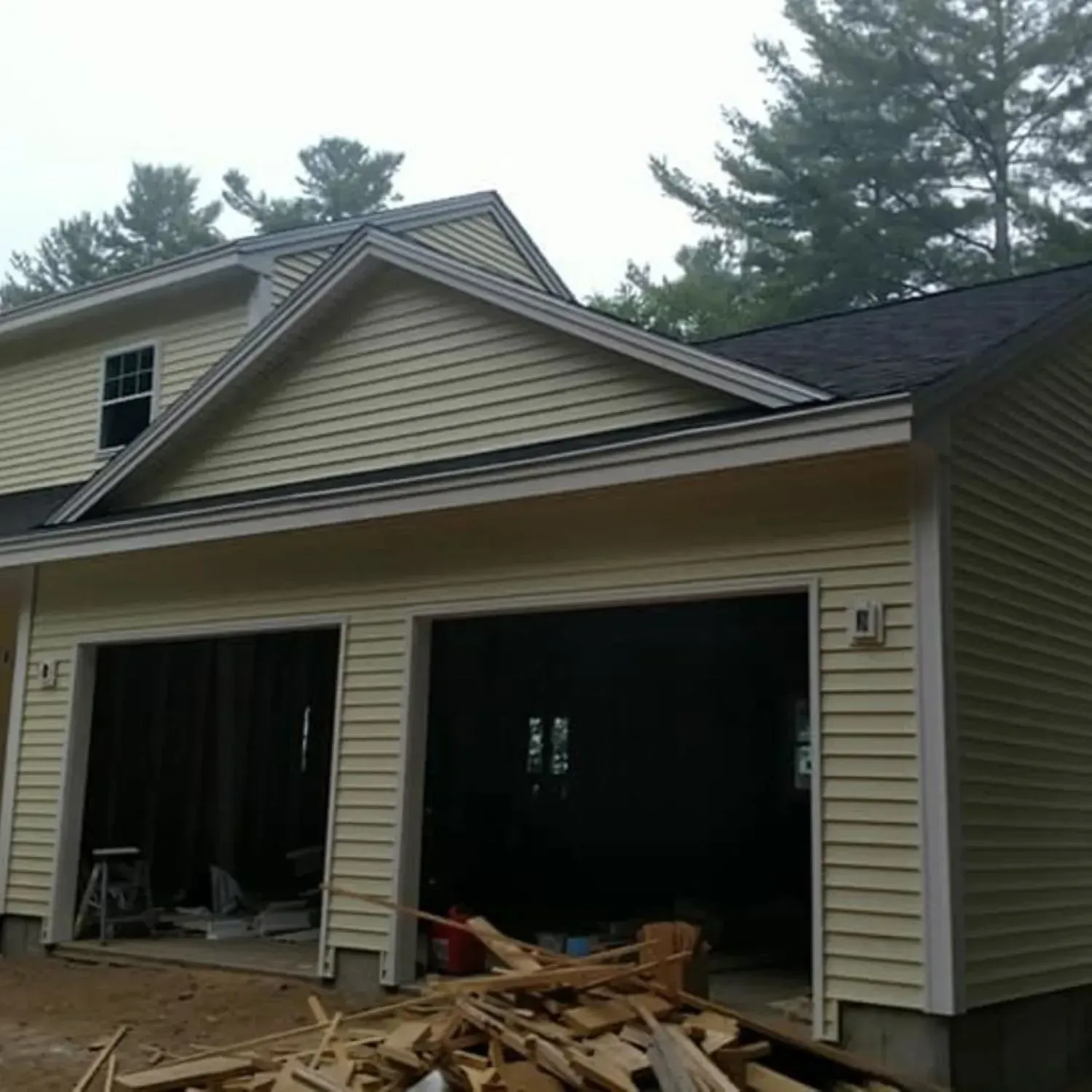 A house under construction with a pile of wood in front of it