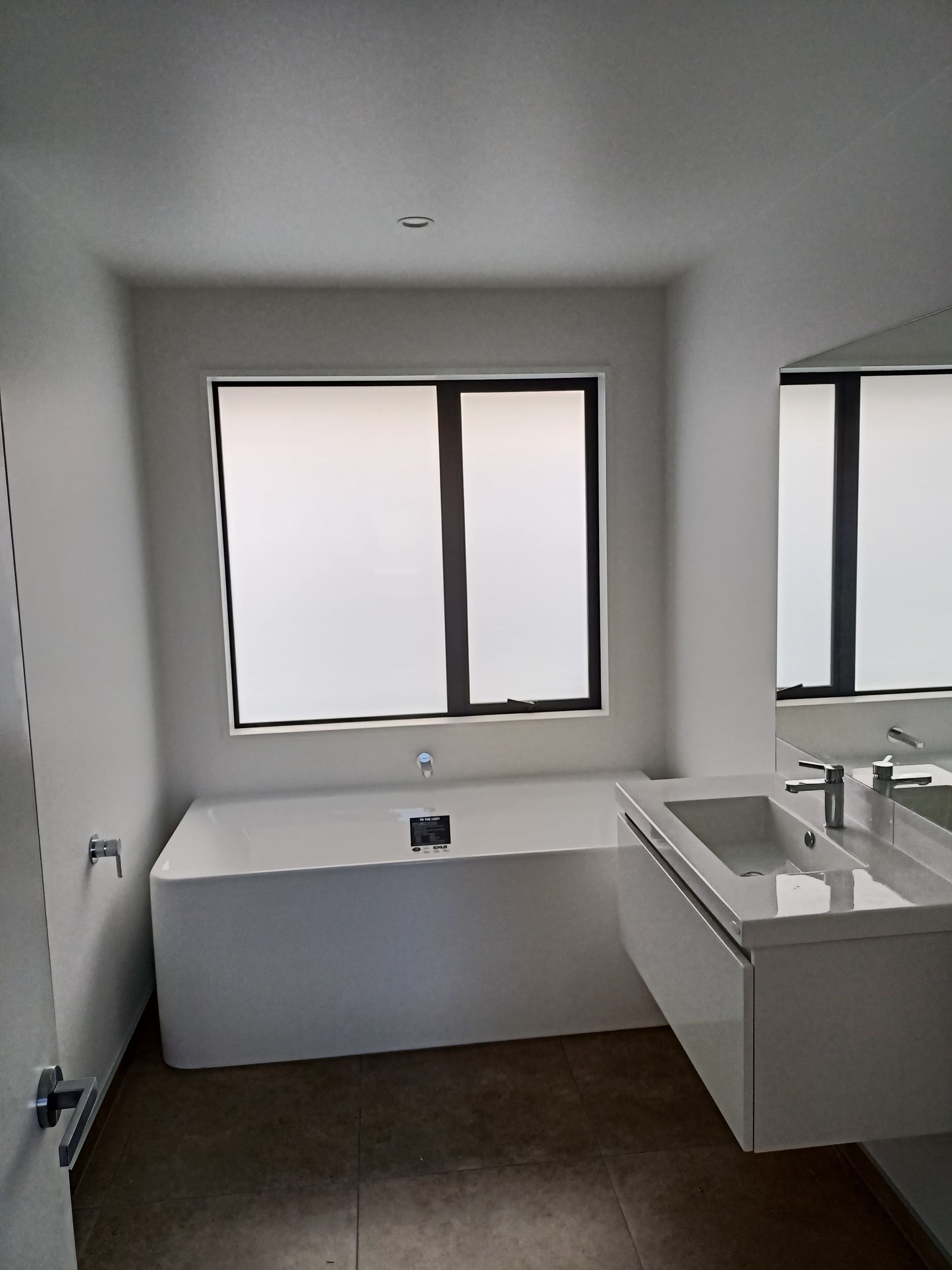 A bathroom with a tub , sink , mirror and window.