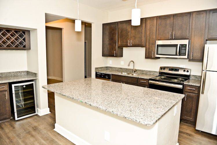 A kitchen with granite counter tops , stainless steel appliances , and wooden cabinets.
