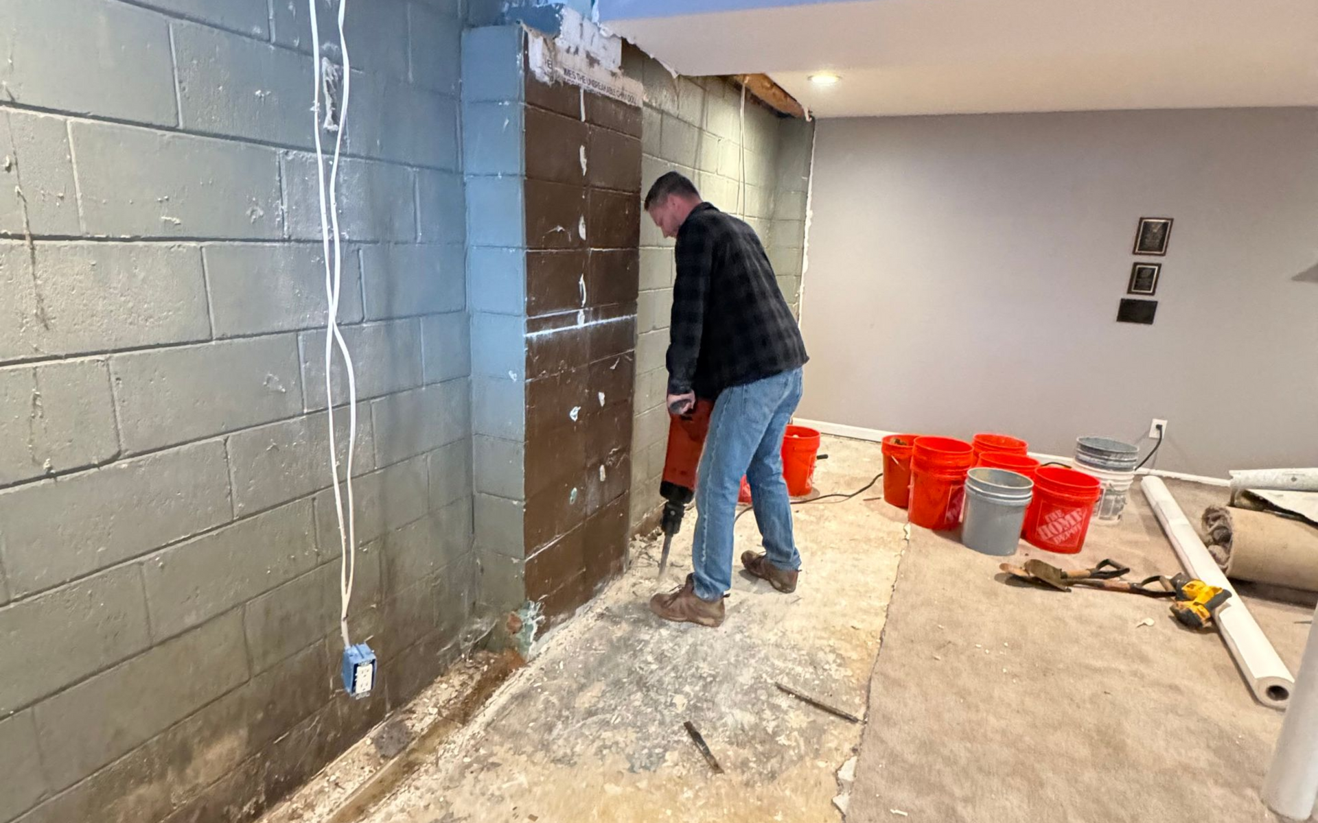Crawlspace with insulation on walls and floor, beams above, pipes, and wooden support beams.
