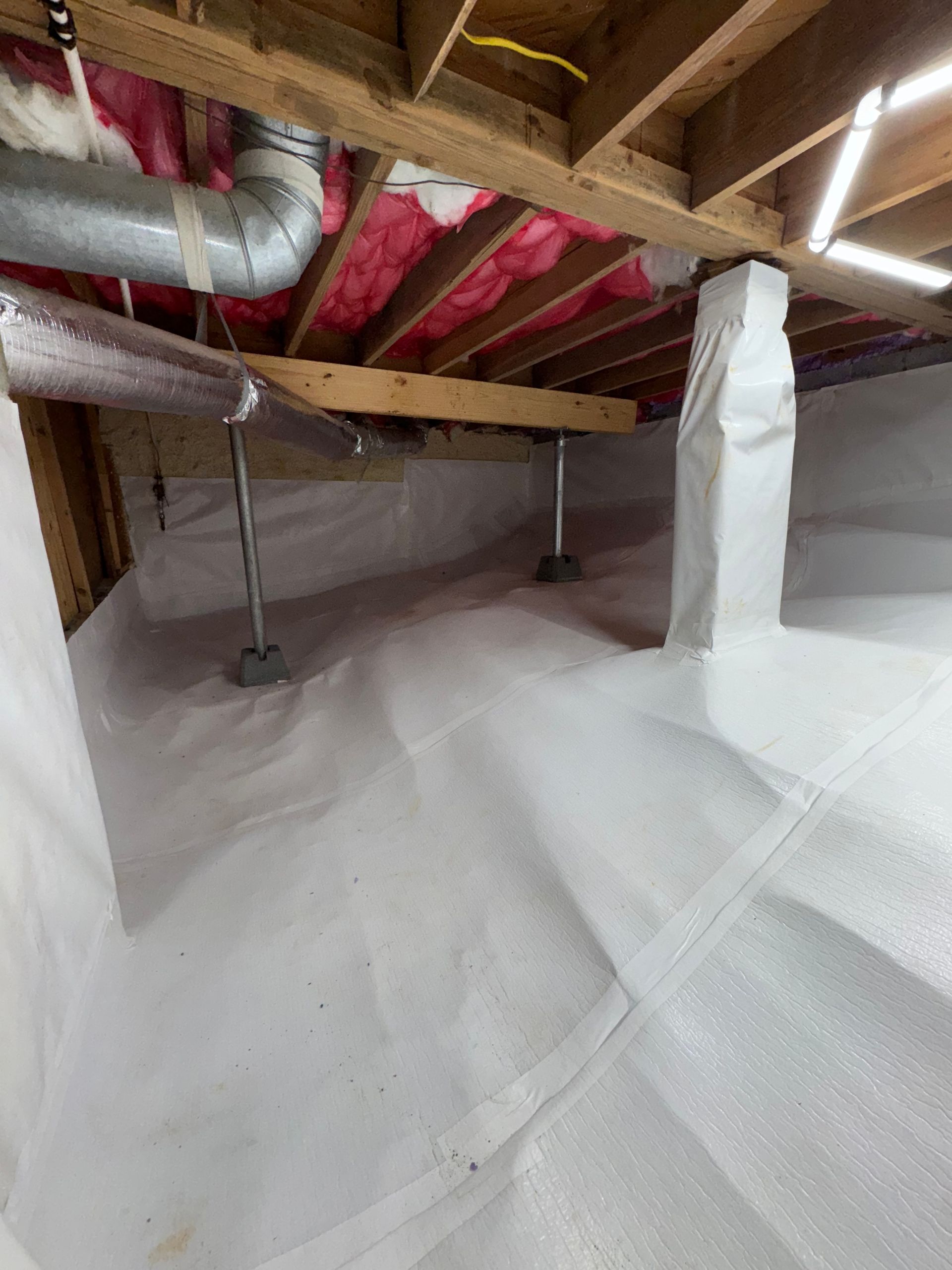 Insulated crawlspace with exposed wooden joists, red ductwork, and white vapor barrier on the floor