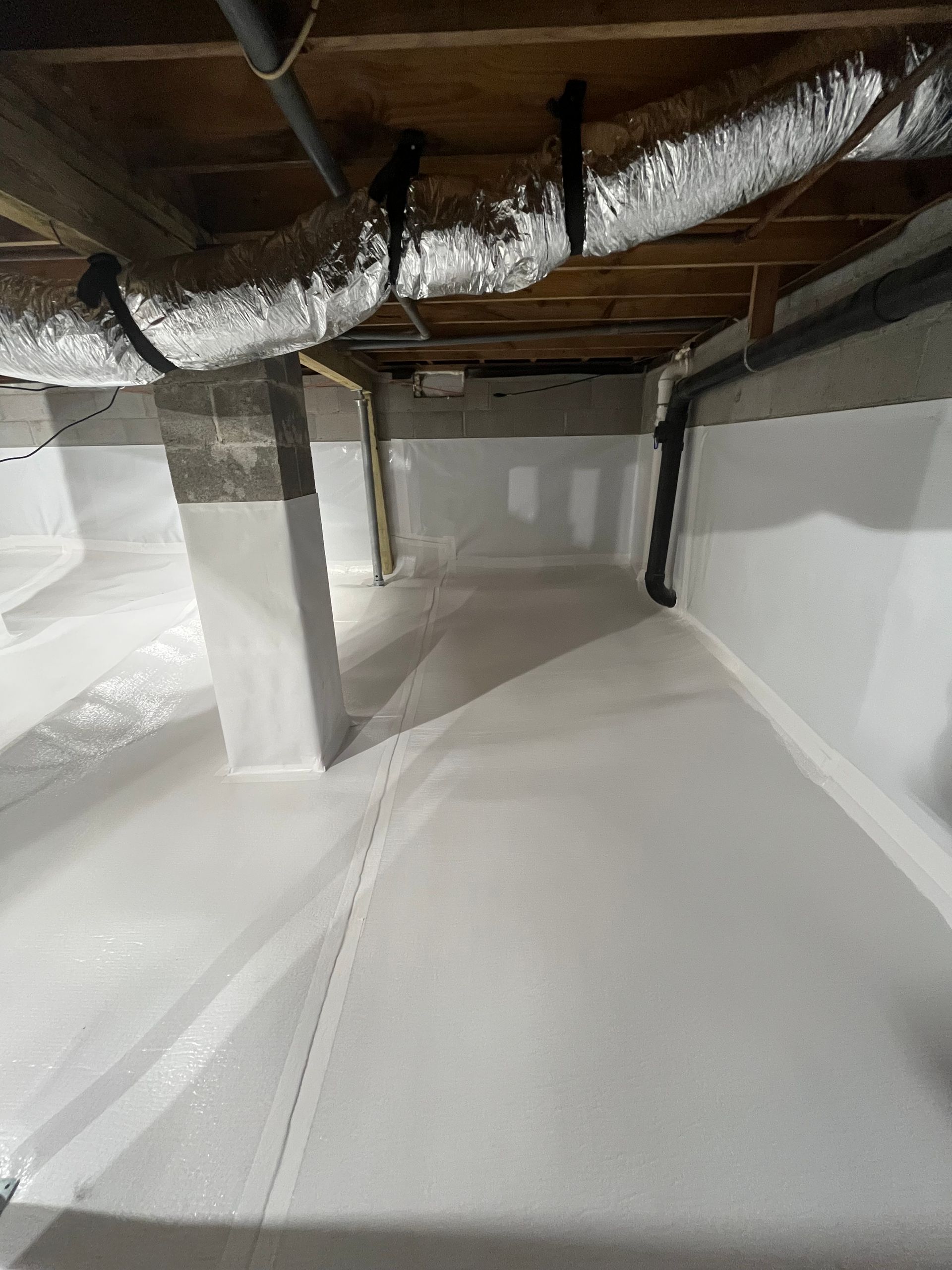 Crawlspace with white insulated walls, exposed wooden joists, and silver ductwork overhead