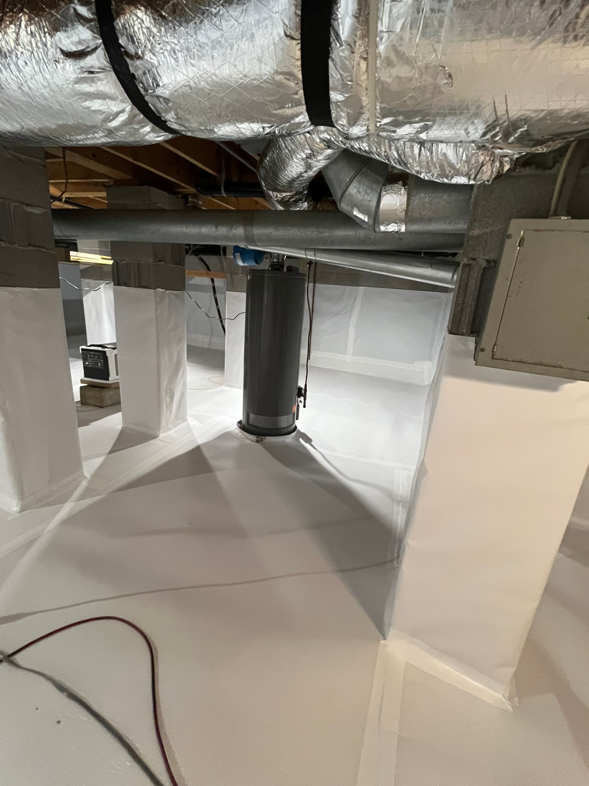 Basement with exposed ducts and pipes, a support column, and a white floor.