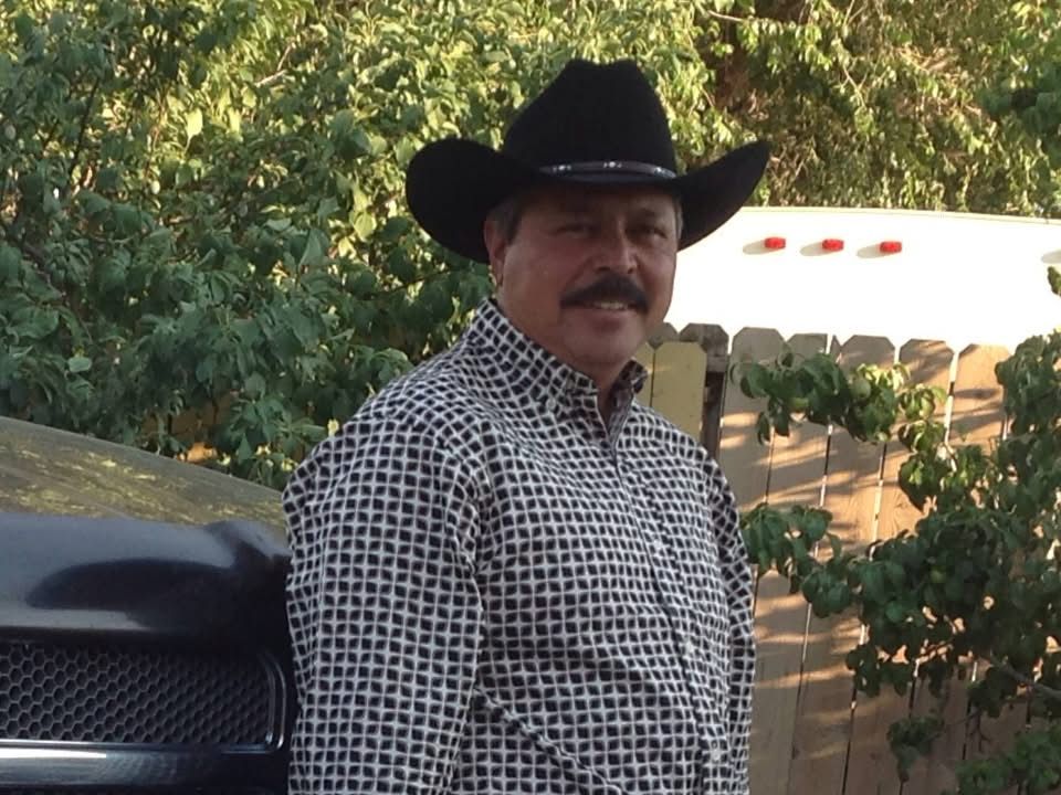 A man wearing a cowboy hat is standing in front of a truck