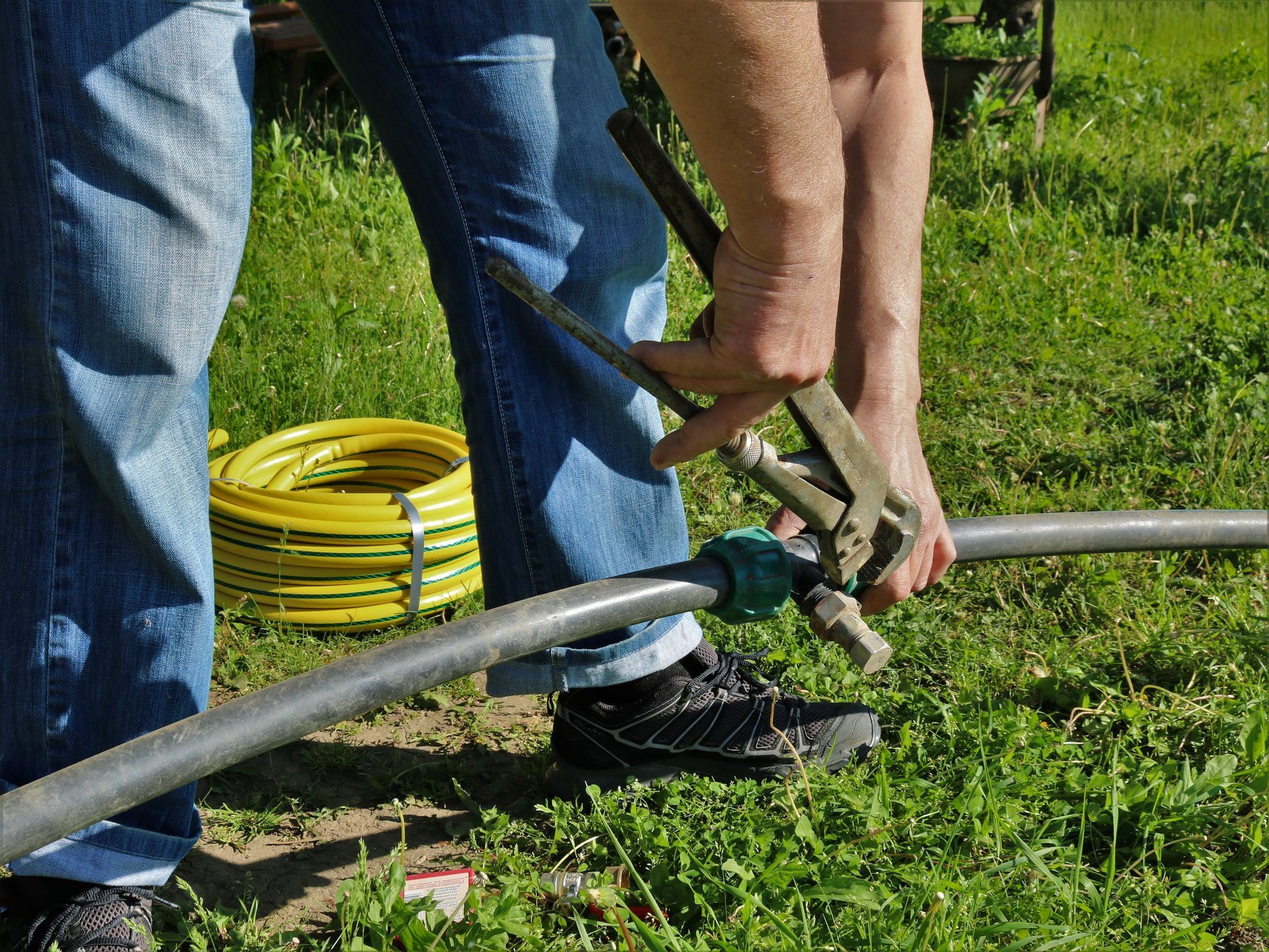 A person is holding a pair of pliers over a hose.