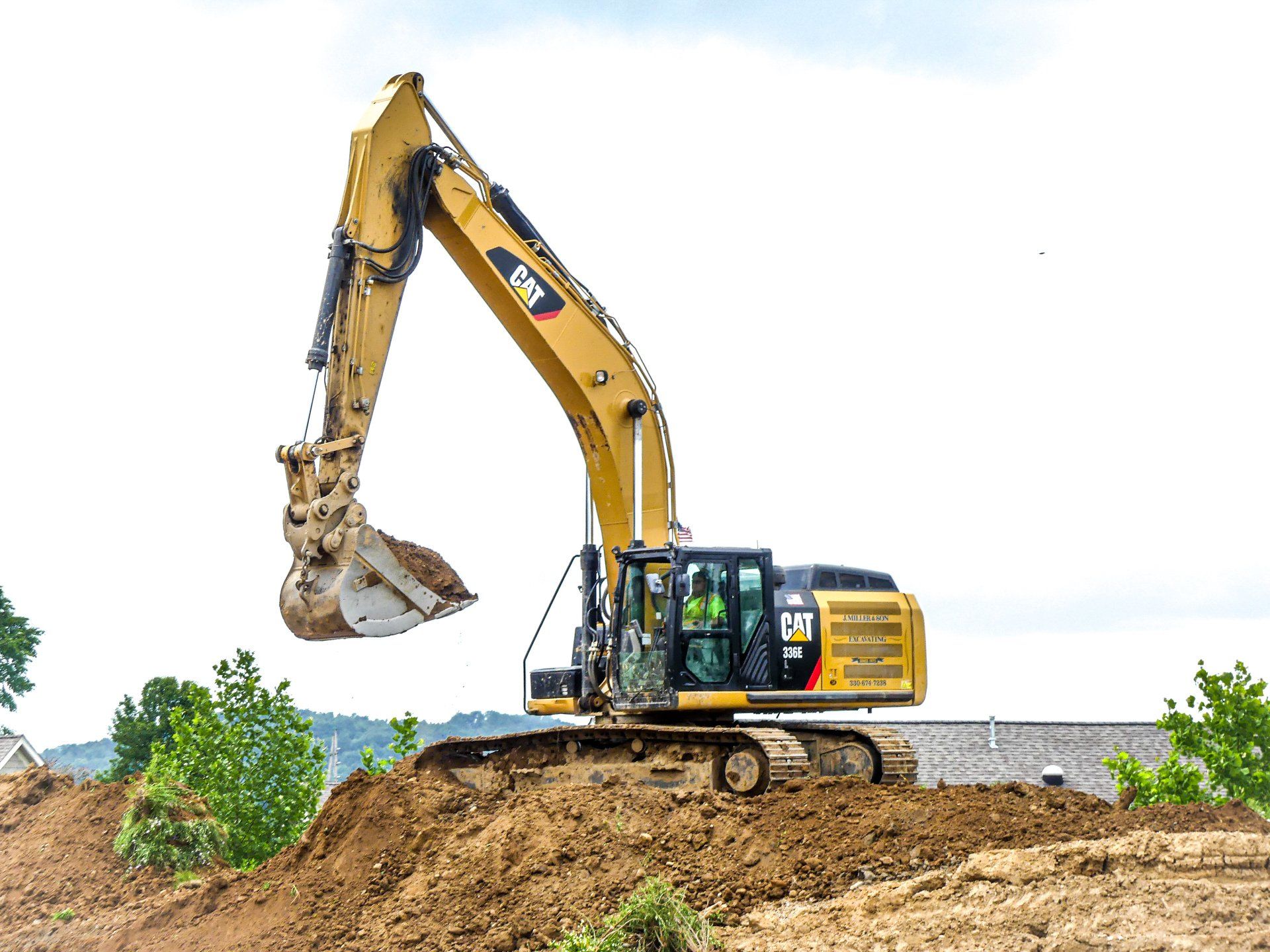 Yellow Caterpillar excavator digging earth on a construction site.