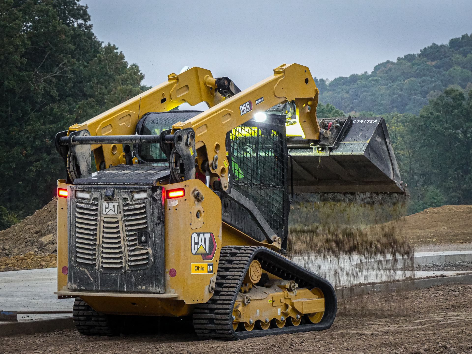 Yellow Caterpillar compact track loader moving dirt.
